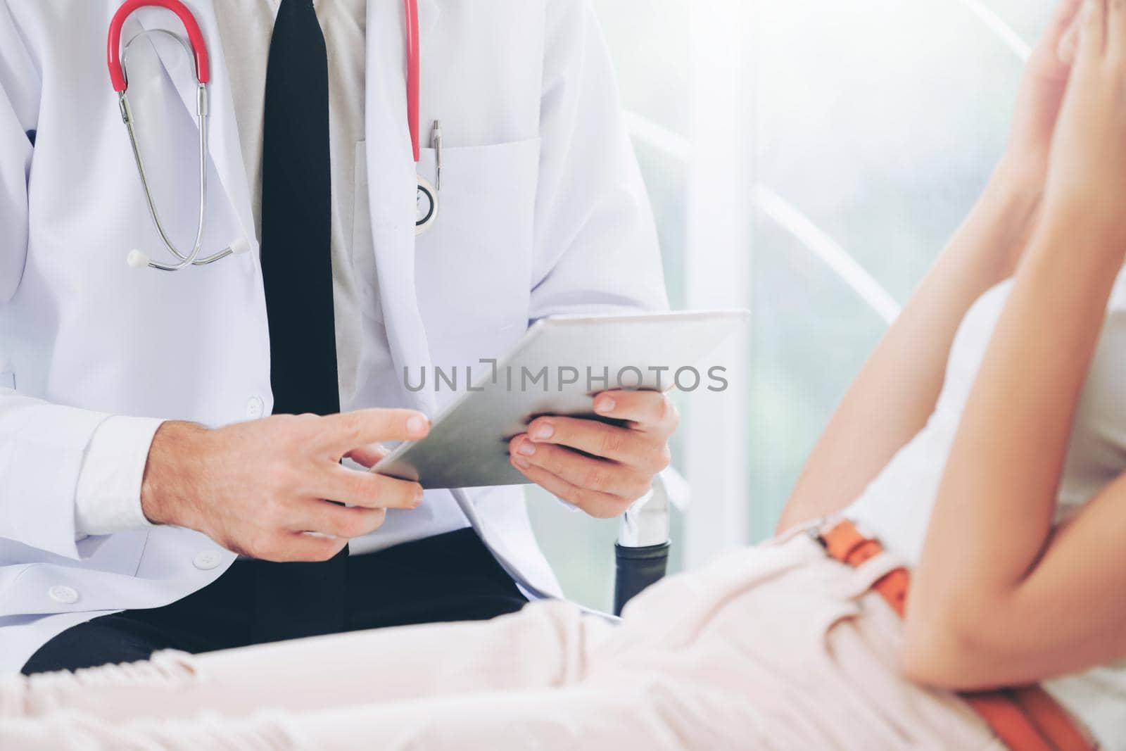 Male doctor is talking and examining female patient in hospital office. Healthcare and medical service.