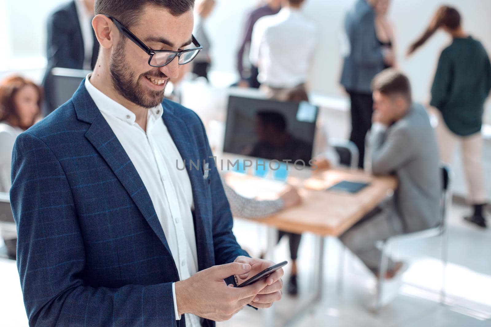 close up. smiling businessman reading correspondence on his smartphone. photo with copy space