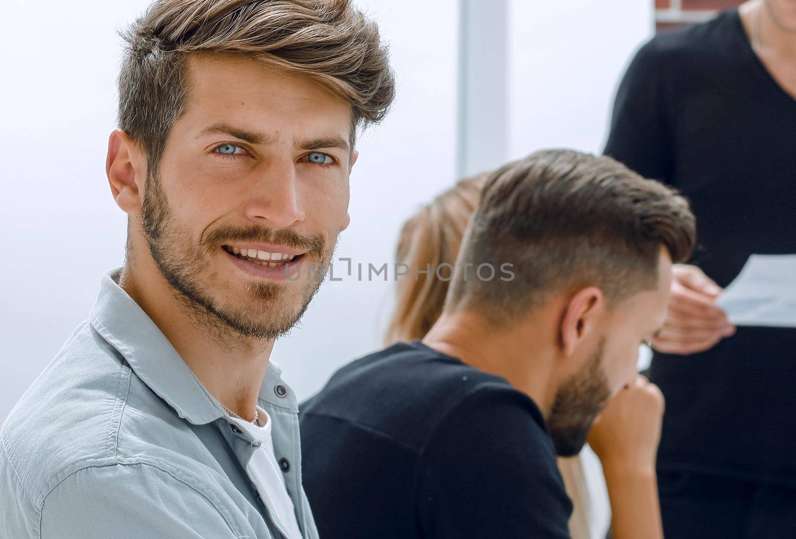 Handsome young men wearing sitting with some of his co-workers in a meeting room