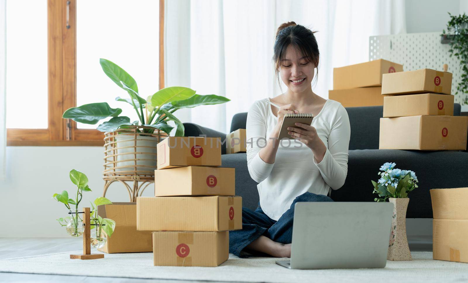 Startup small business owner working with computer at workplace. Freelance woman seller check product order. Packing goods for delivery to customer. Online selling. E-commerce.