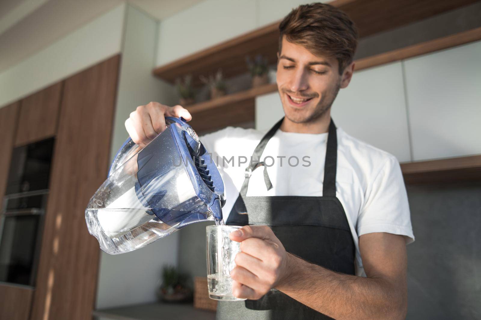 close up. a young man pours clean water into a glass