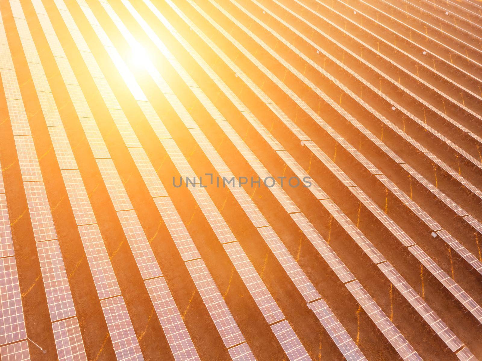 Aerial top view of a solar panels power plant. Photovoltaic solar panels at sunrise and sunset in countryside from above. Modern technology, climate care, earth saving, renewable energy concept