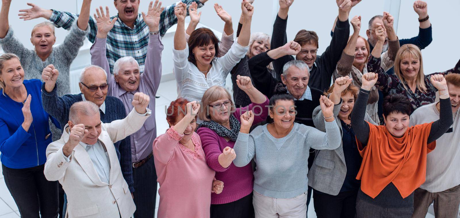 group of elderly friends raised their hands up and celebrate suc by asdf