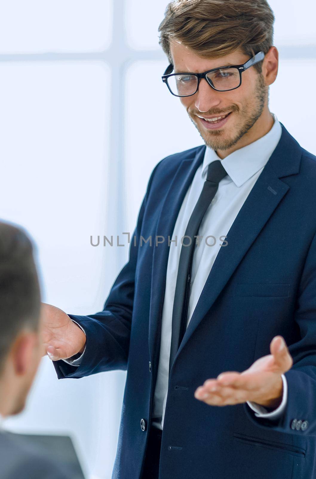 two businessmen at the office greeting each other by the hand and smiling