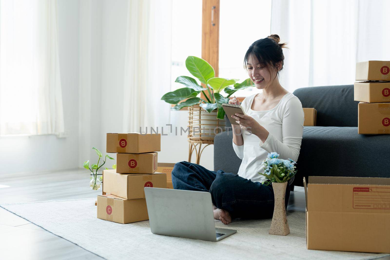 Startup small business owner working with computer at workplace. Freelance woman seller check product order. Packing goods for delivery to customer. Online selling. E-commerce.