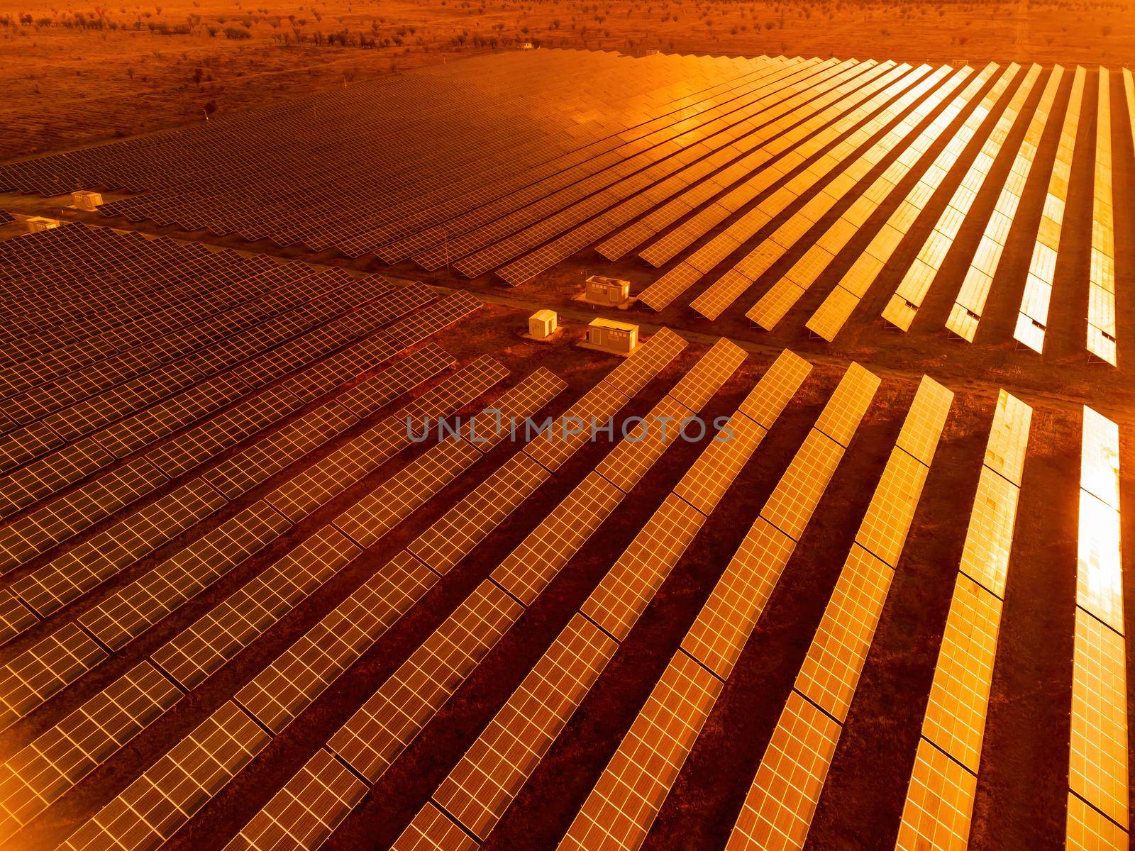 Aerial top view of a solar panels power plant. Photovoltaic solar panels at sunrise and sunset in countryside from above. Modern technology, climate care, earth saving, renewable energy concept