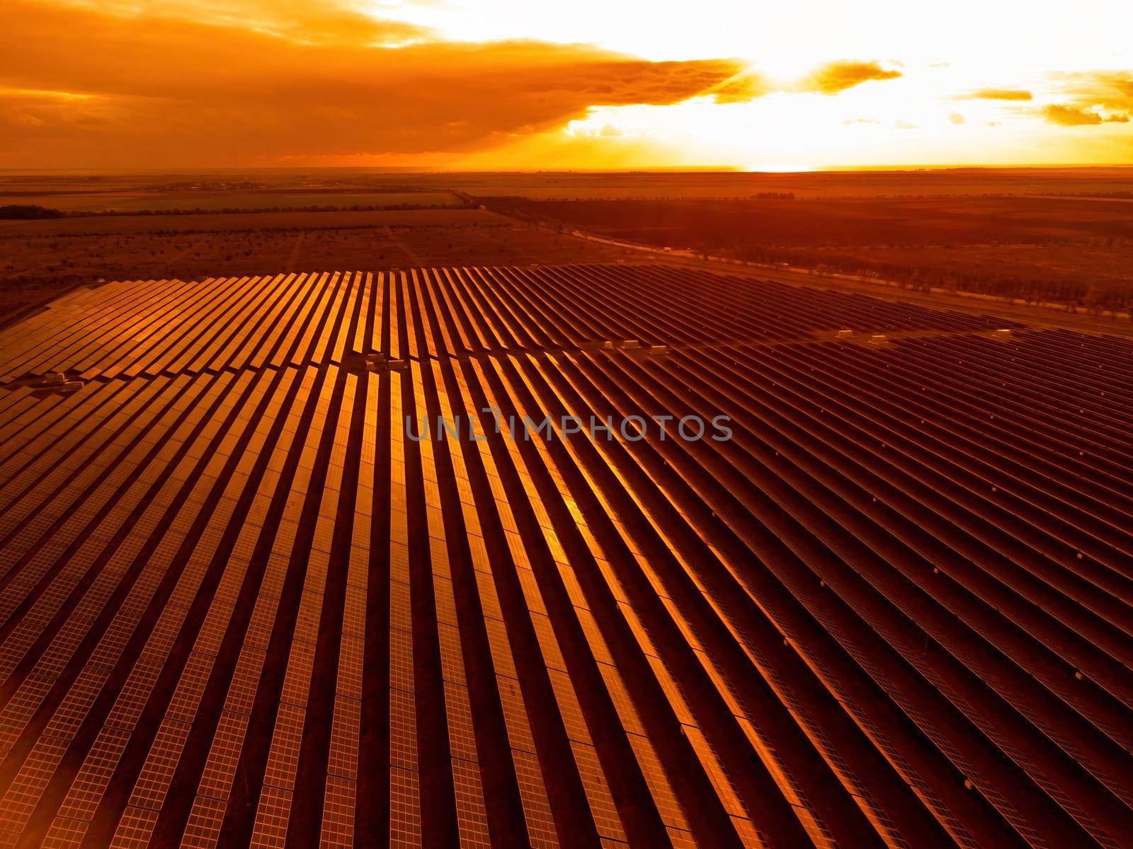 Aerial top view of a solar panels power plant. Photovoltaic solar panels at sunrise and sunset in countryside from above. Modern technology, climate care, earth saving, renewable energy concept