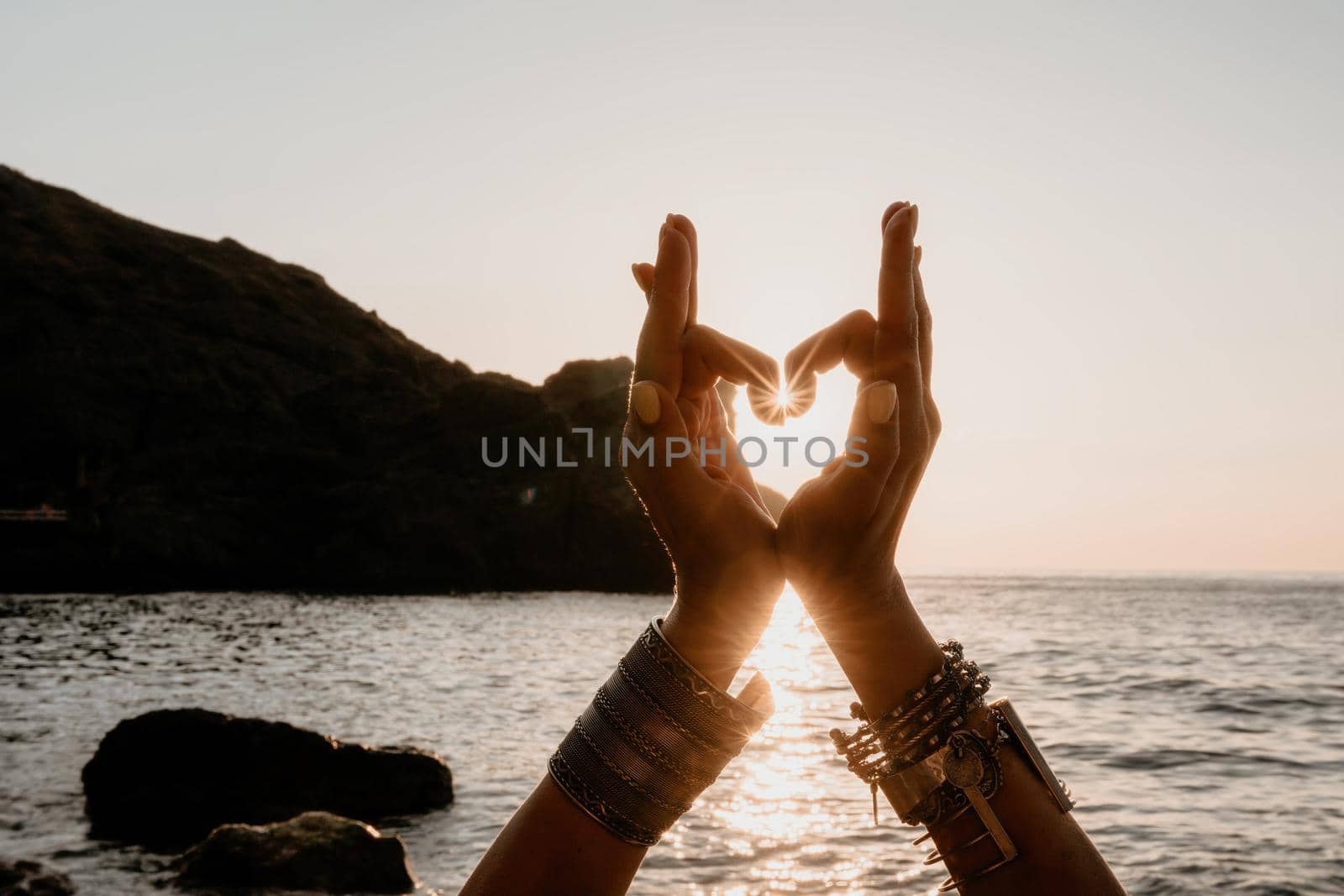 Young woman in swimsuit with long hair practicing stretching outdoors on yoga mat by the sea on a sunny day. Women's yoga fitness pilates routine. Healthy lifestyle, harmony and meditation concept.