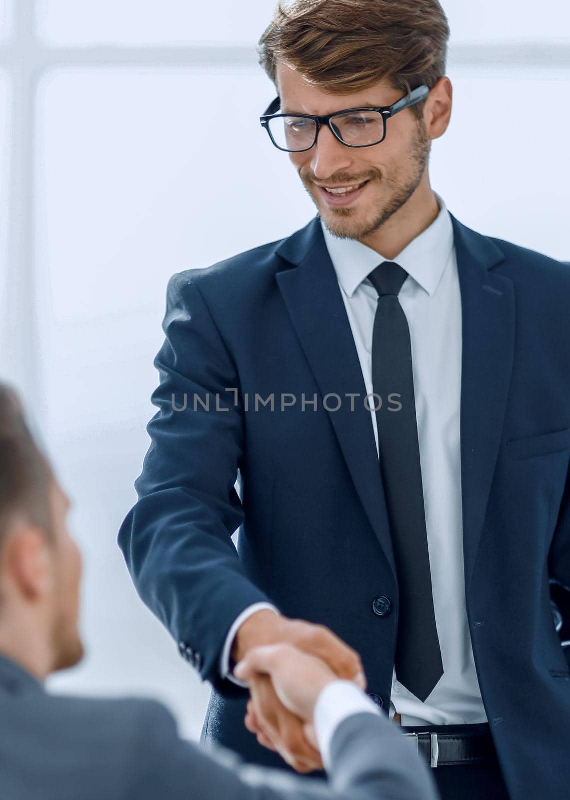 young businessman with glasses greets his colleague with a handshake