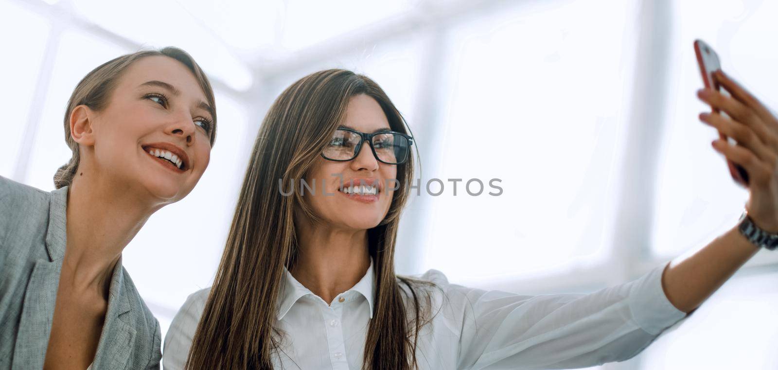 two attractive business women take selfies .photo with text space