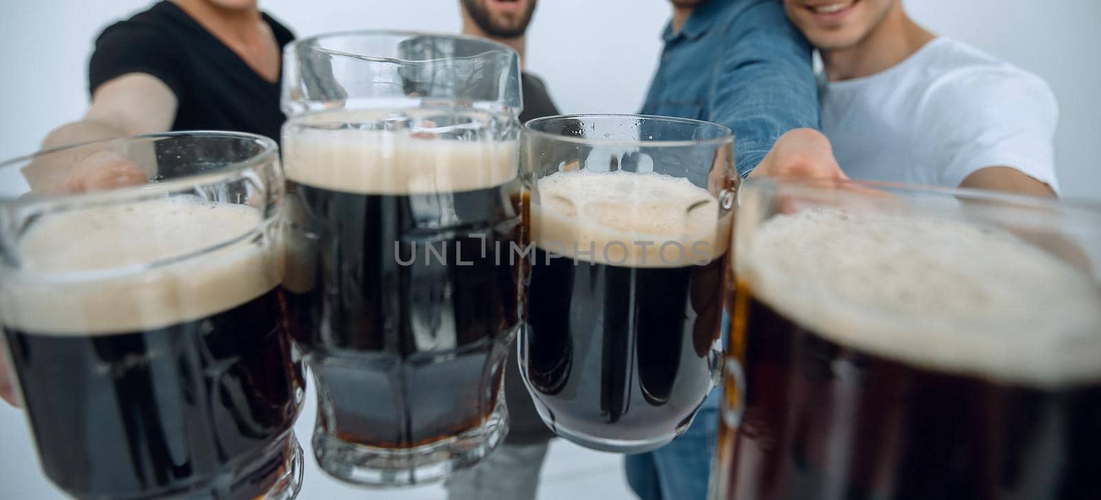 close up.mugs of beer in the hands of a group of men.holiday concept