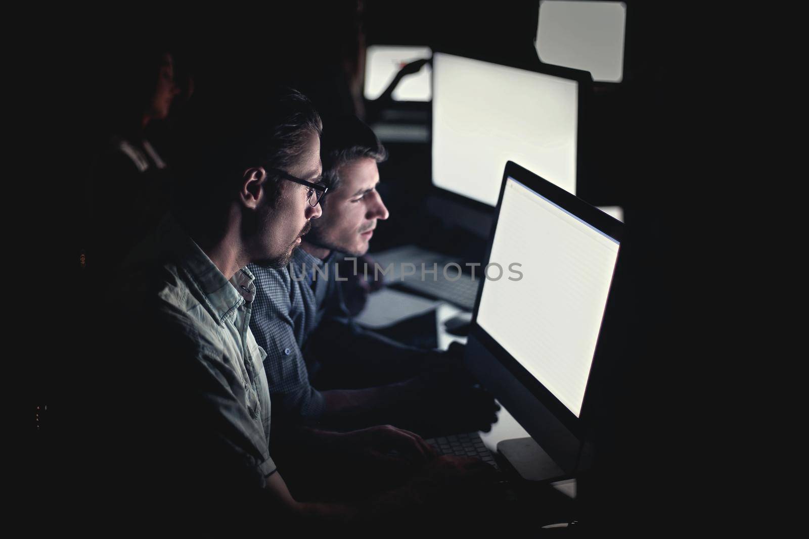 business team works on computers at night. by asdf
