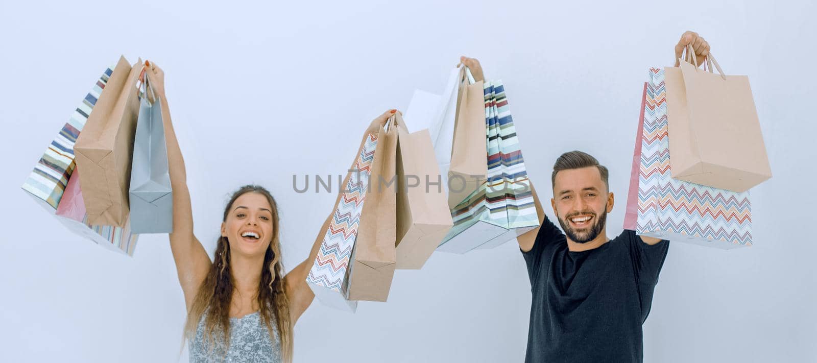 young couple holding shopping bags and looking at the camera isolated on white background