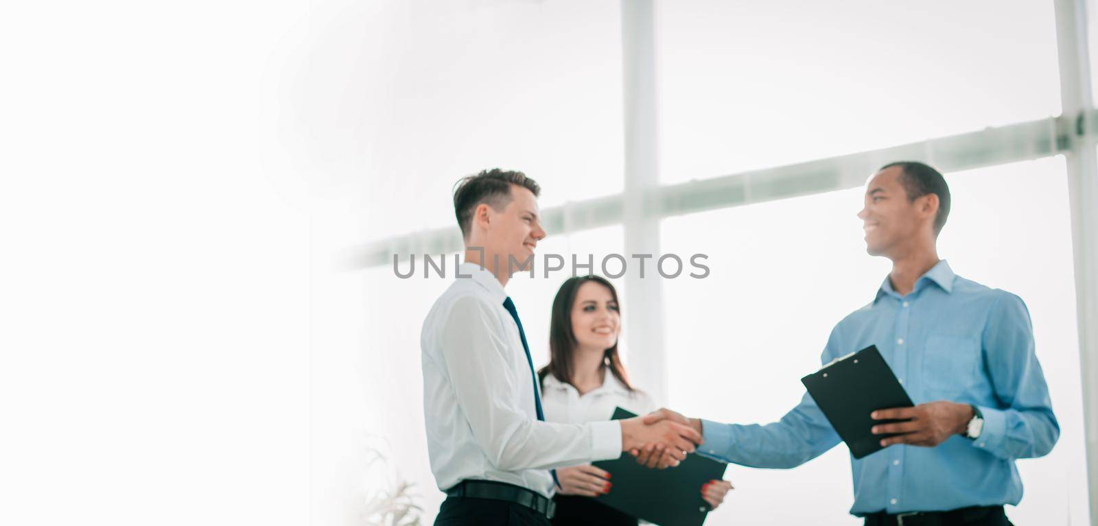 friendly business people shaking hands on blurred background by SmartPhotoLab
