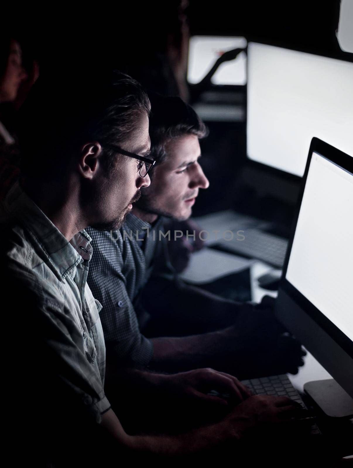 business team works on computers at night. by asdf