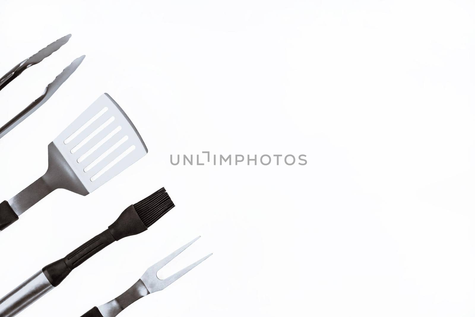 Set with barbecue utensils on white background. Stainless steel spatula, oil brush, tongs, fork for bbq. Copy space by JuliaDorian