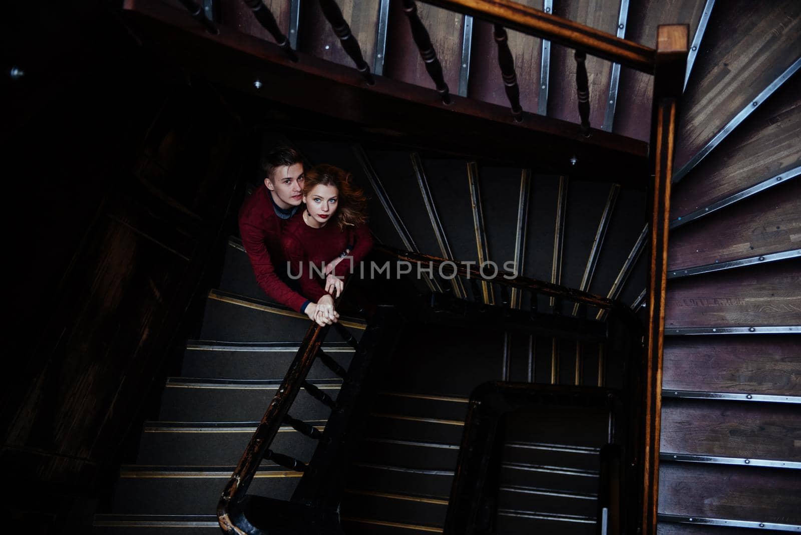 couple of young people on the wooden stairs in the entrance of an old house