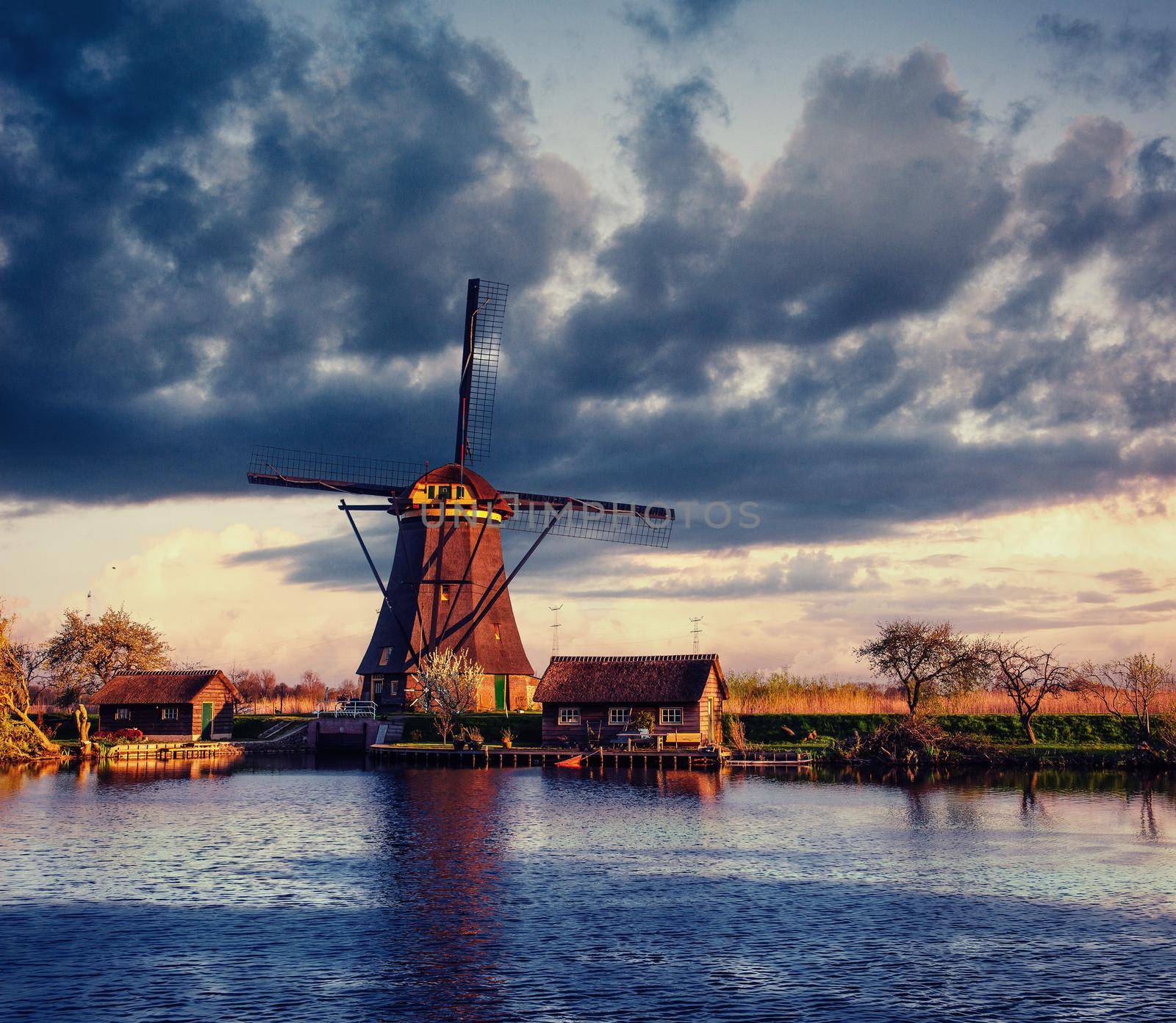 Colorful spring day with traditional Dutch windmills canal in Rotterdam. Wooden pier near the lake shore. Holland. Netherlands.