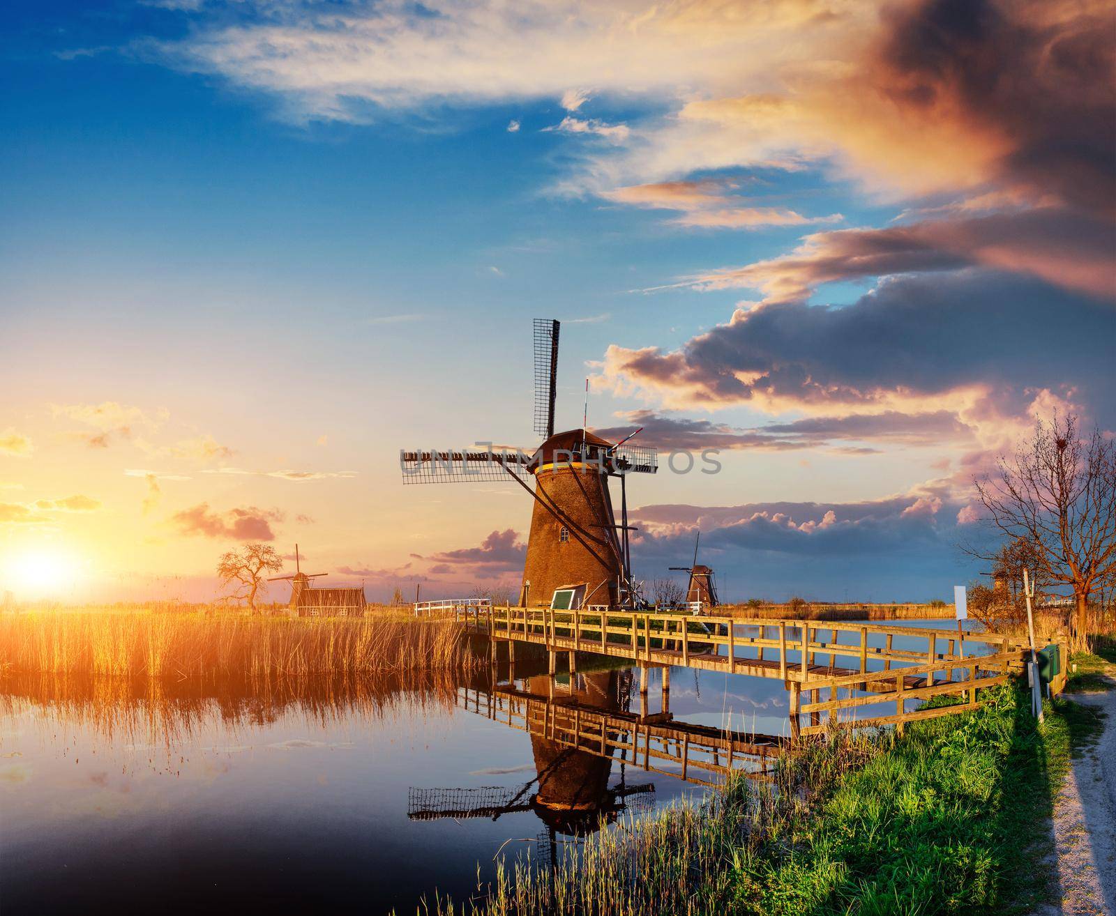 Colorful spring day with traditional Dutch windmills canal in Rotterdam. Wooden pier near the lake shore. Holland. Netherlands.