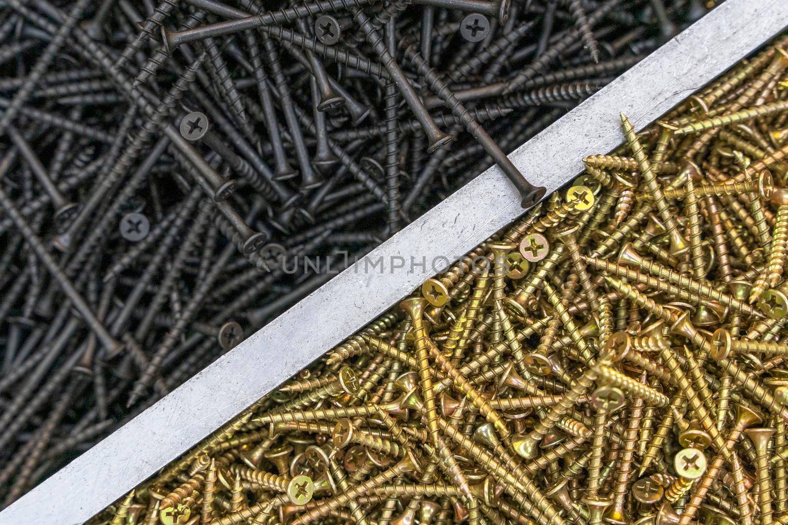 Gold and black metal galvanized screws. Industrial textured background made of self-tapping screws.