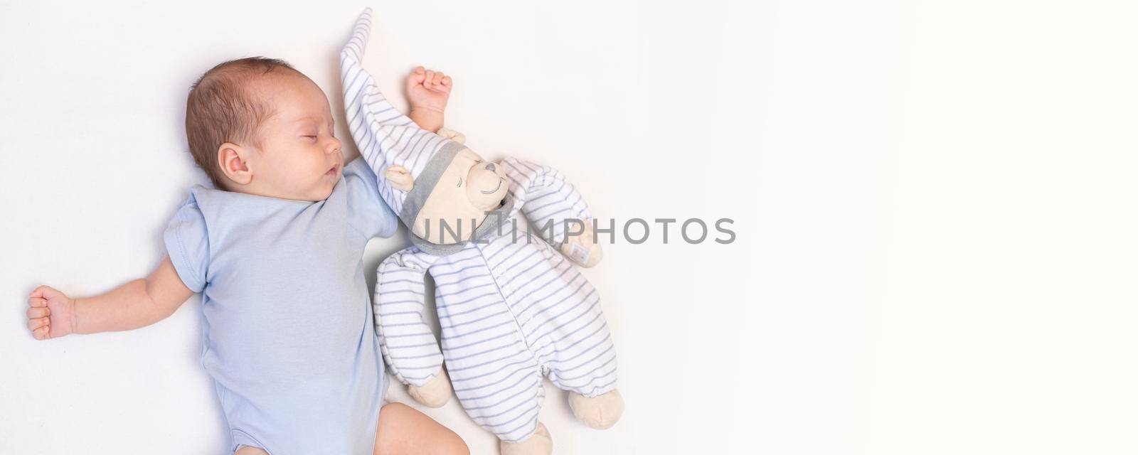 The baby is lying in a crib with a teddy bear . The baby is 0-3 months old. A calm sleeping baby. Healthy baby sleep. An article about toys for kids. A soft toy. Copy space banner