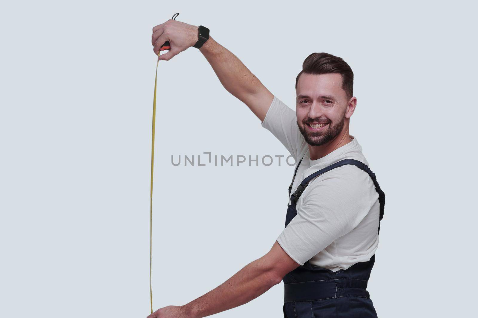 in full growth. smiling man showing construction - roulette. isolated on white background