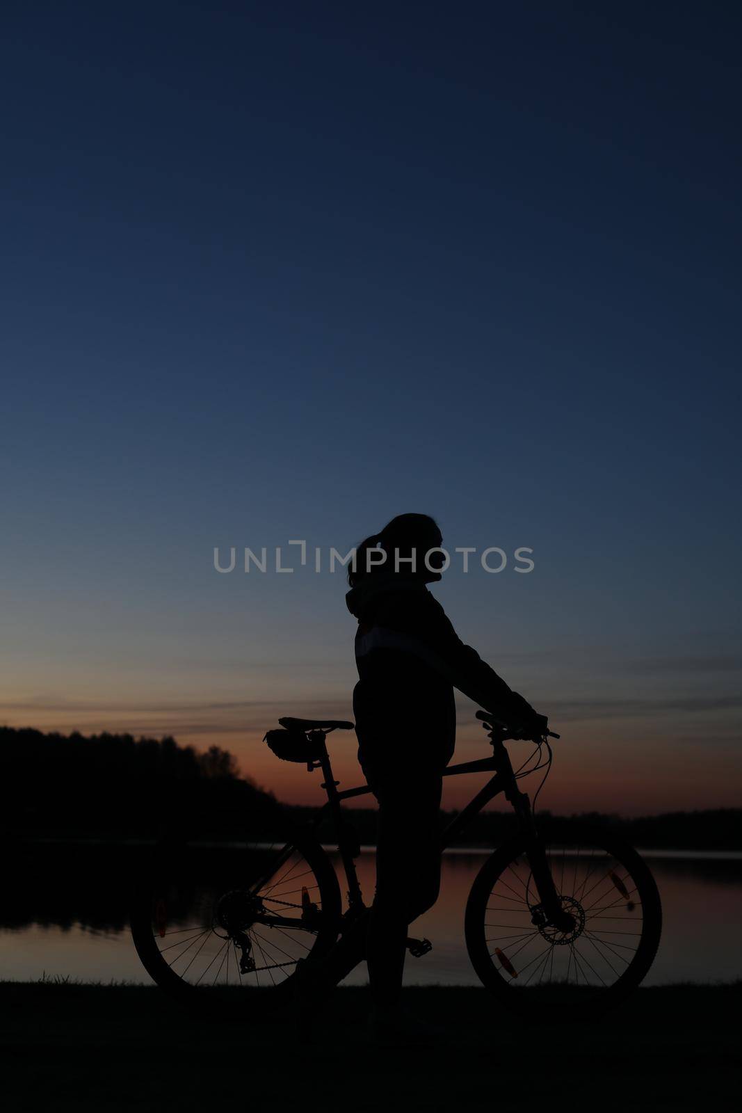 Silhouette of woman with a bike at sunset. Active outdoors lifestyle for healthy concept.