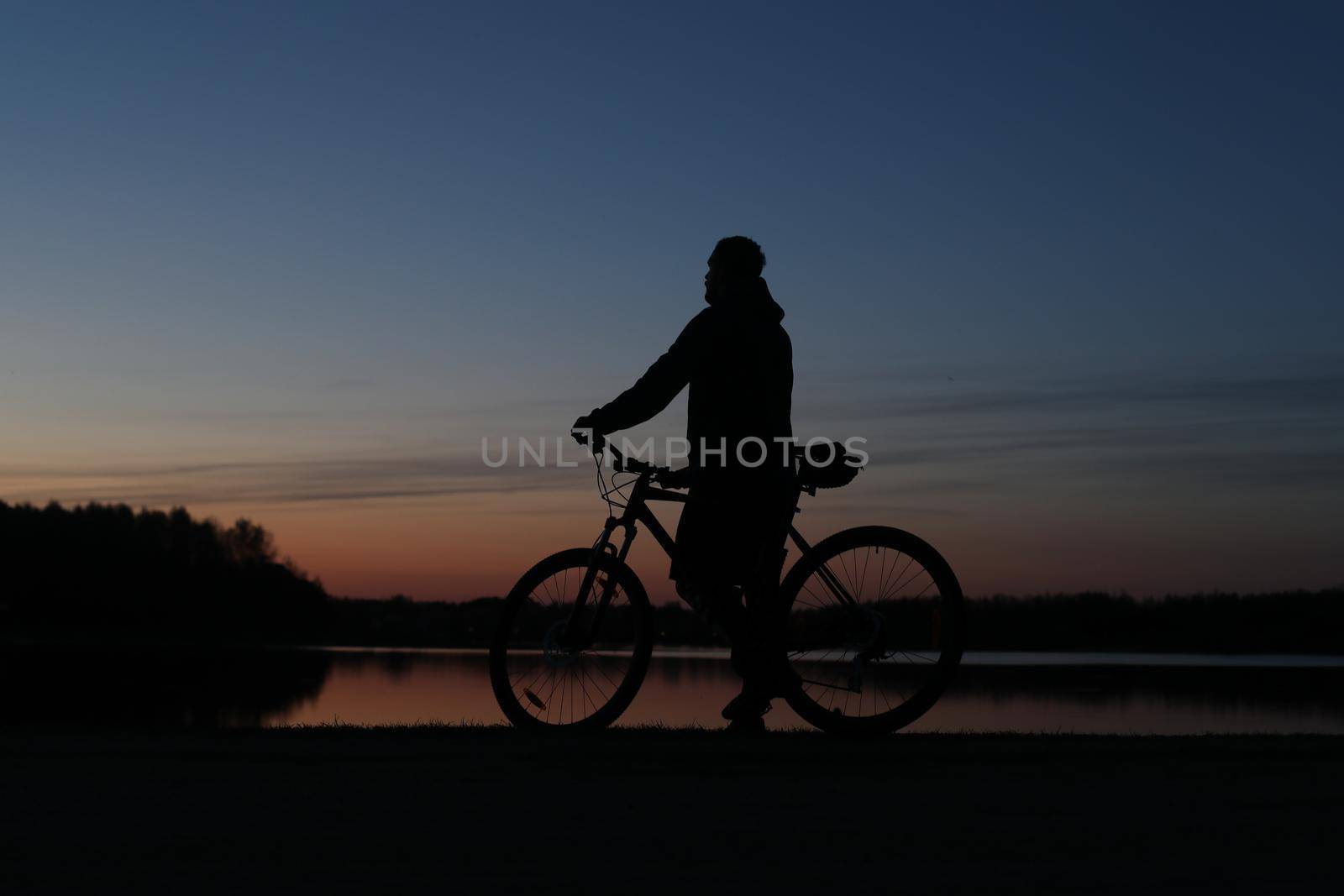 Silhouette of a cyclist on the beach at sunset.