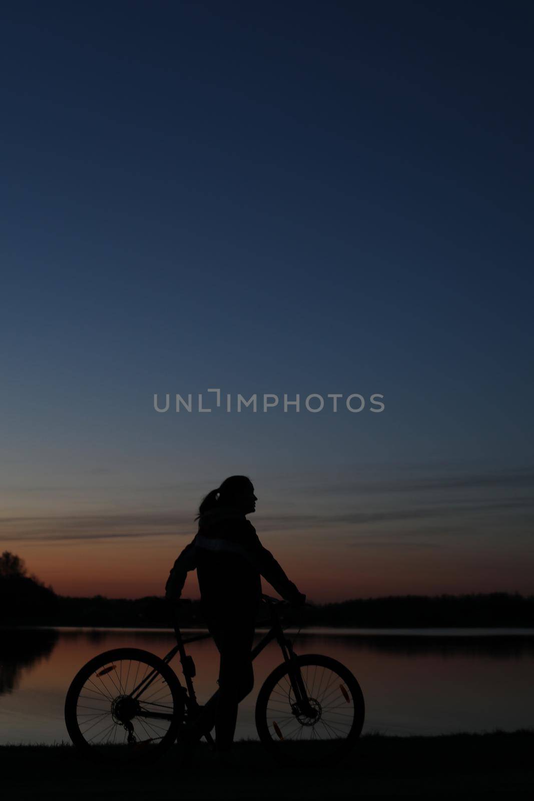 Silhouette of woman with a bike at sunset. Active outdoors lifestyle for healthy concept.