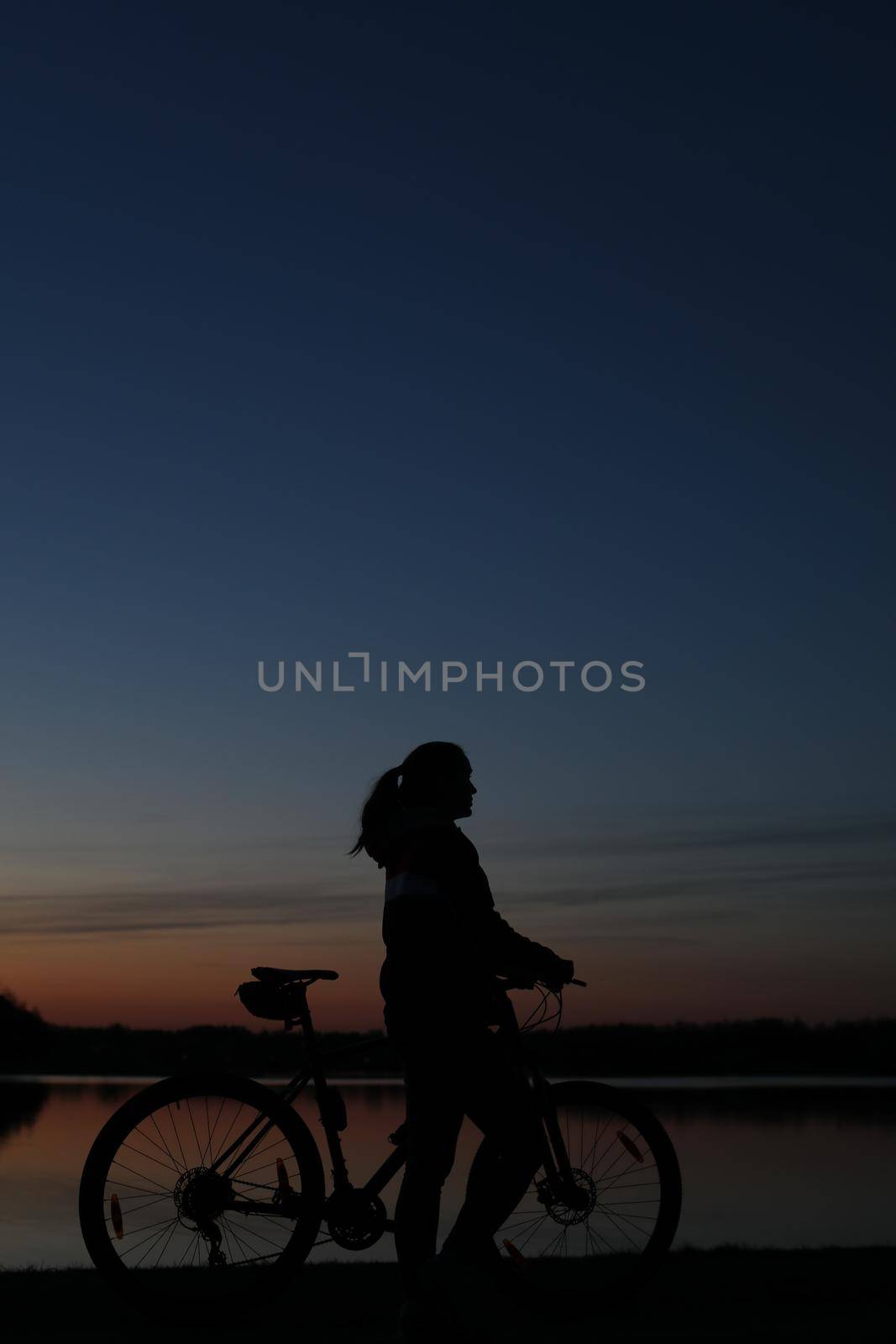 Silhouette of woman with a bike at sunset. Active outdoors lifestyle for healthy concept.