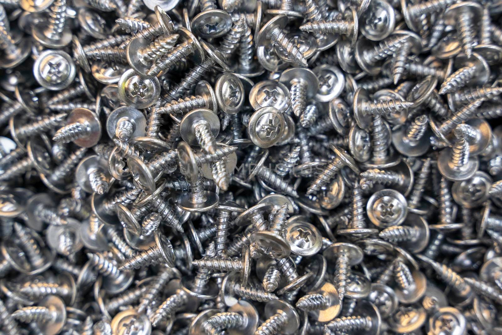 A lot of metal galvanized self-tapping screws. Industrial texture background of self-tapping screws.