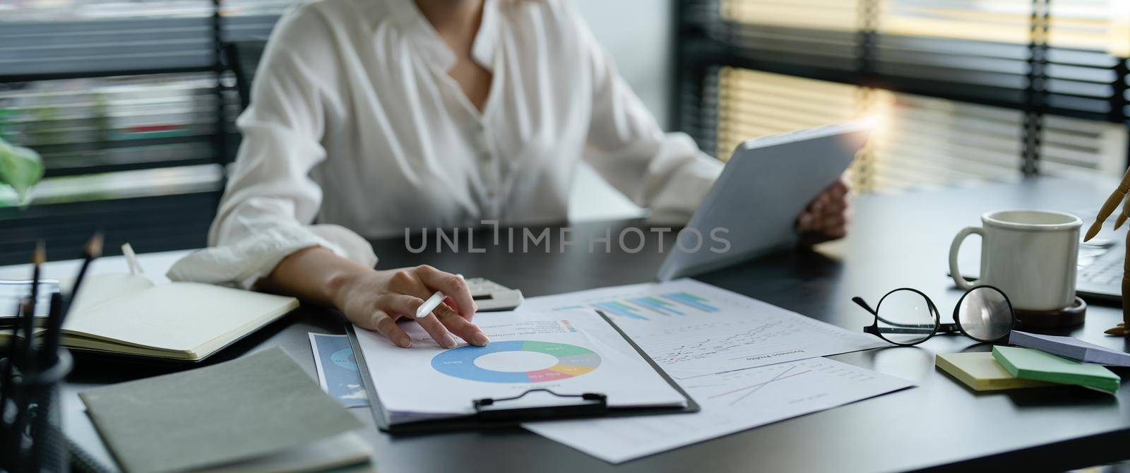 Close up business woman hand holding stylus pen and digital tablet for planning working schedule in office.