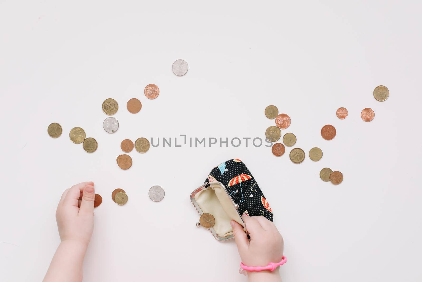 Toddler girl hands play with coins. Learning financial responsibility and planning savings concept