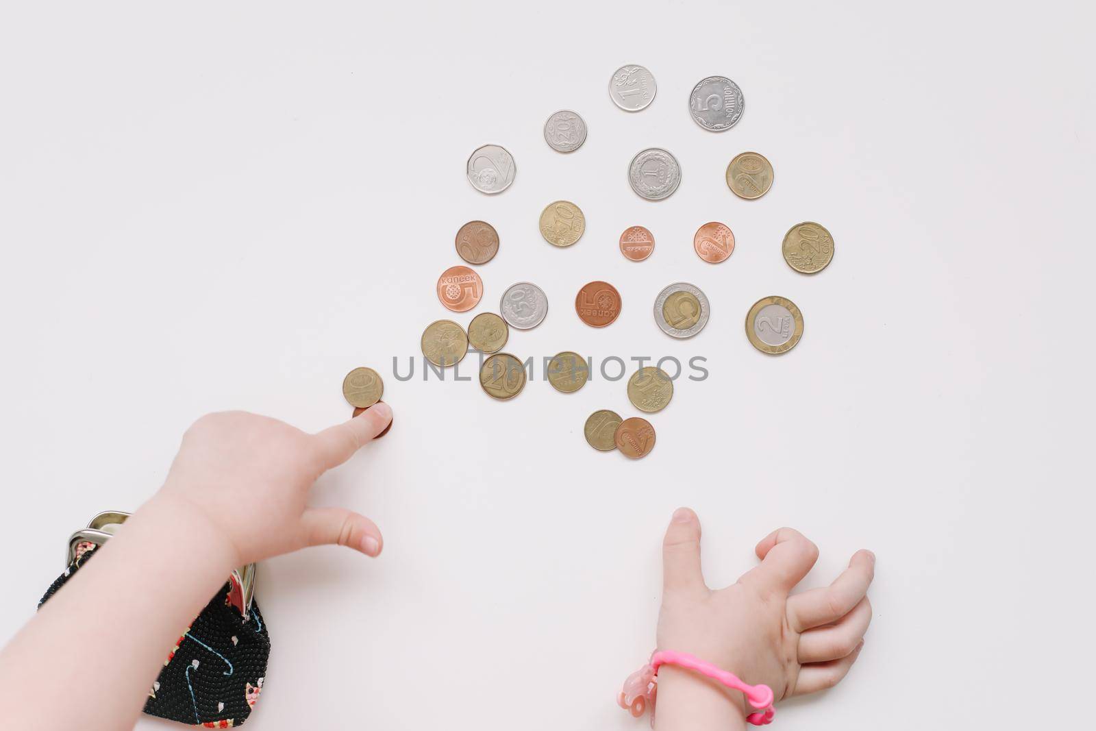 Toddler girl hands play with coins. Learning financial responsibility and planning savings concept