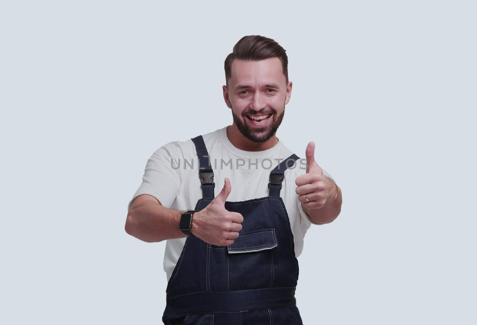 in full growth. friendly man in overalls showing thumbs up. isolated on white background