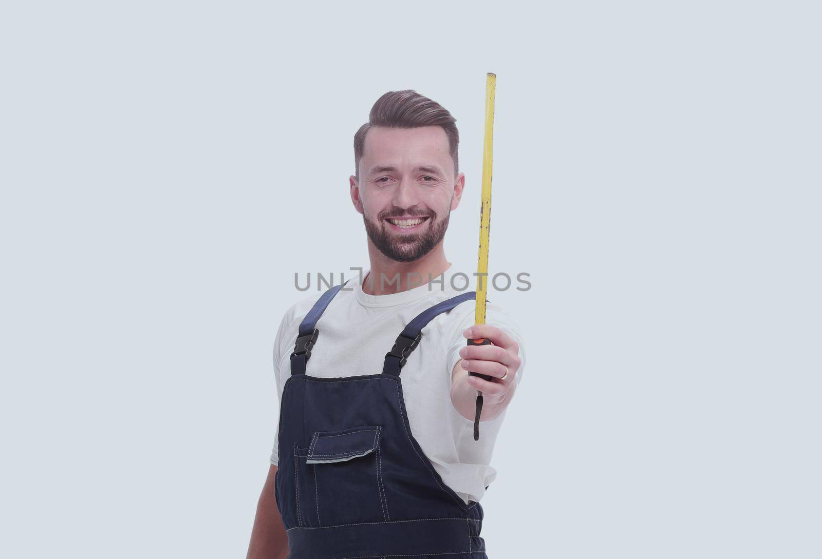 in full growth. a man in overalls with a construction tape measure. isolated on white background