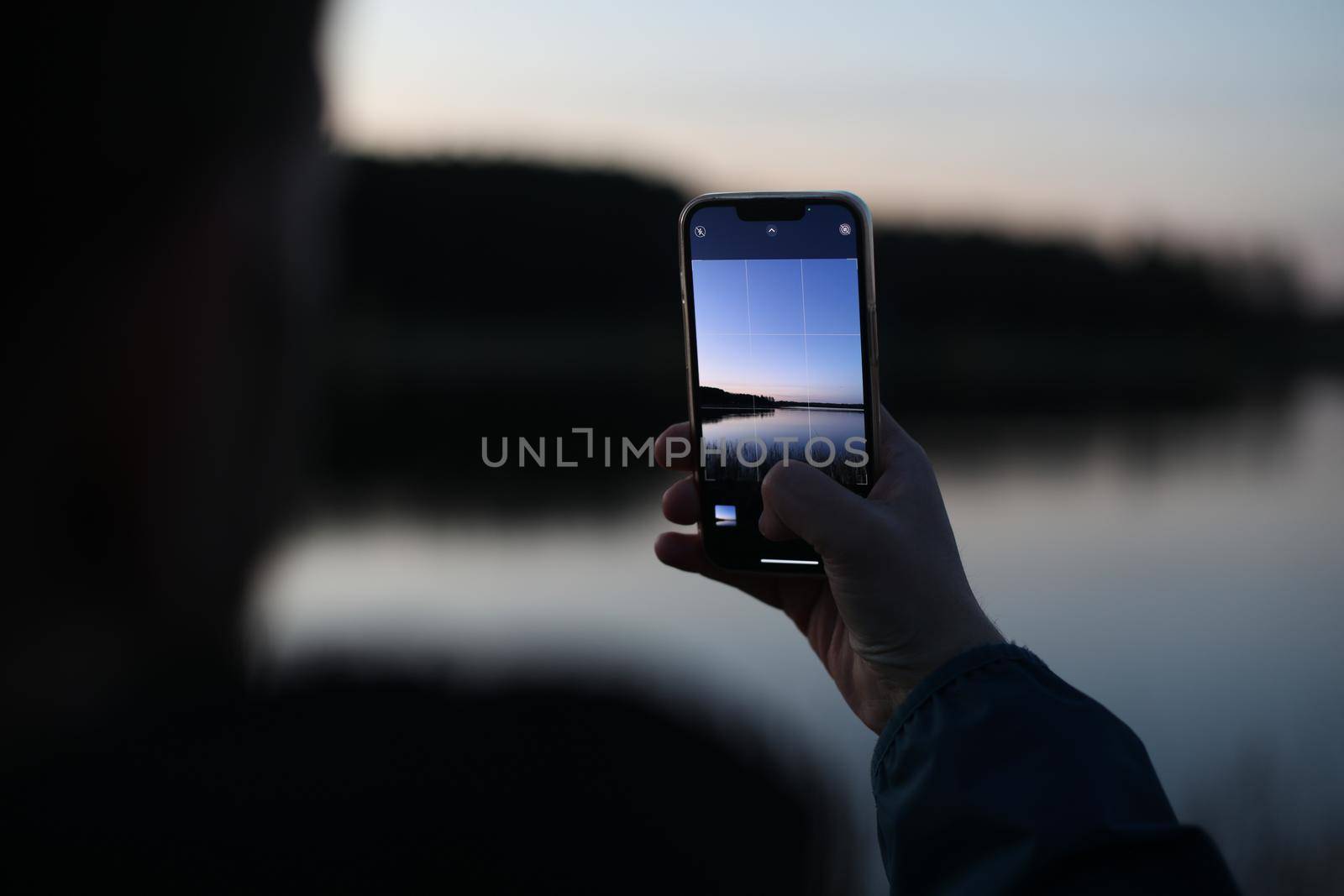 hand holding smart phone and taking photo of beautiful sunset by paralisart