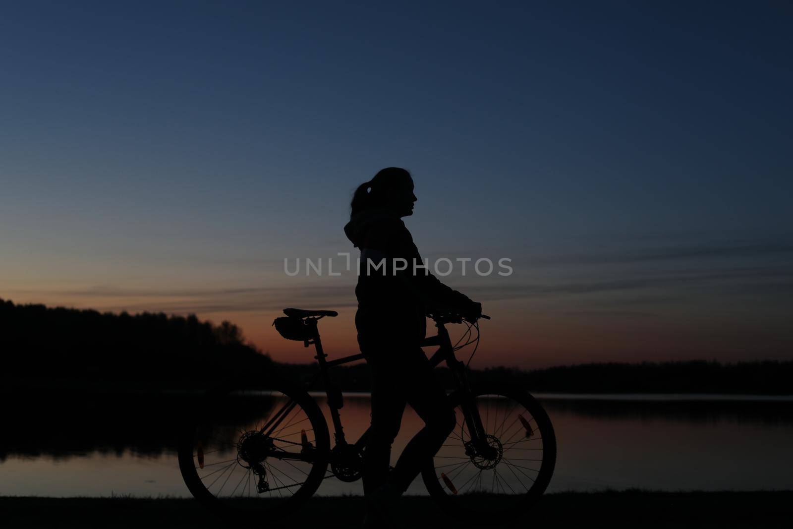 Silhouette of woman with a bike at sunset. Active outdoors lifestyle for healthy concept.
