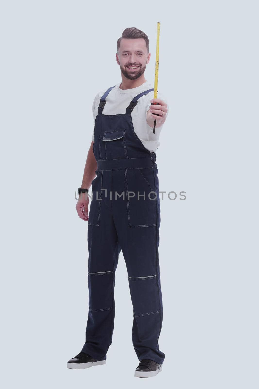 in full growth. a man in overalls with a construction tape measure. isolated on white background