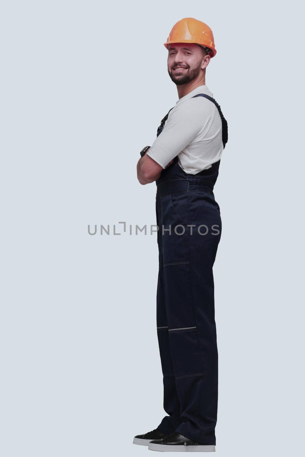 in full growth. smiling man in overalls and a safety helmet . isolated on white background