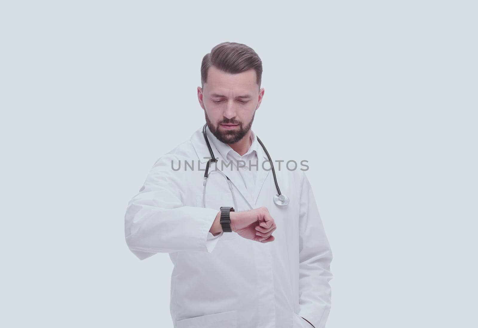 in full growth. medical doctor looking at his wrist watch. isolated on white background