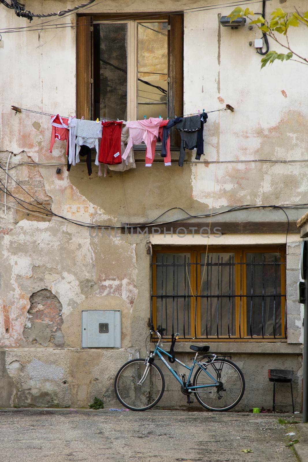 Street picture showing a facade with a window and some clothes hanging over a bicycle