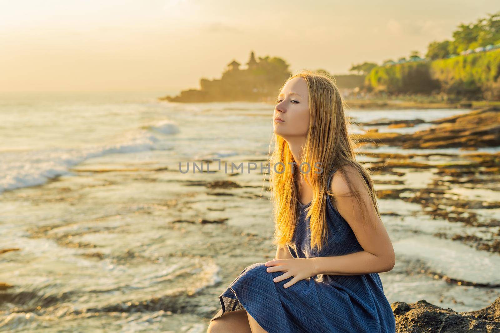 Young woman tourist on the background of Tanah Lot - Temple in the Ocean. Bali, Indonesia.