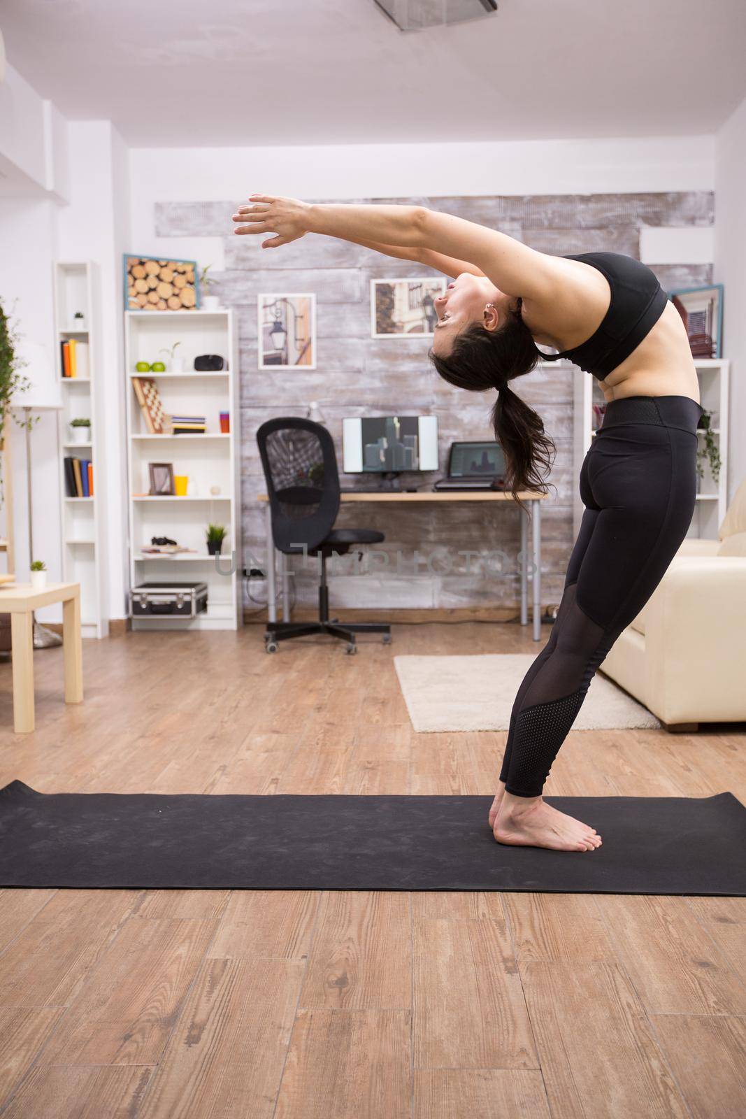 Young woman in leggings standing and leaning backward to relax her body.