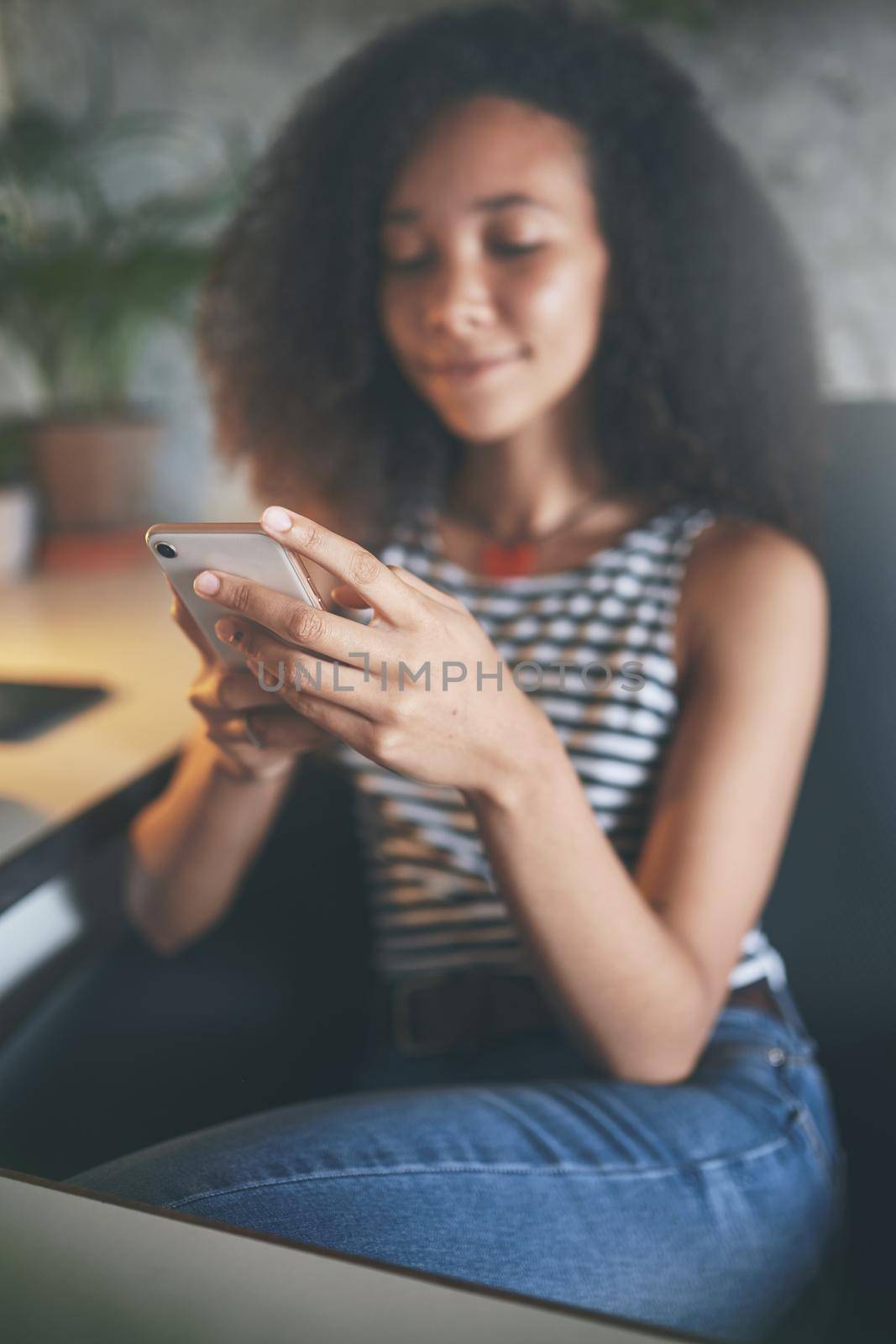 Shot of an attractive young african woman sitting alone and using technology while working from home stock photo