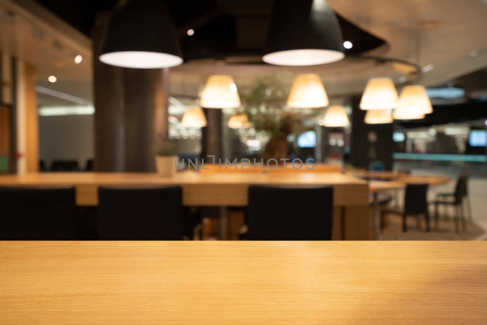 Wood table in blurry background of modern restaurant room or coffee shop with empty copy space on the table for product display mockup. Interior restaurant counter design concept.