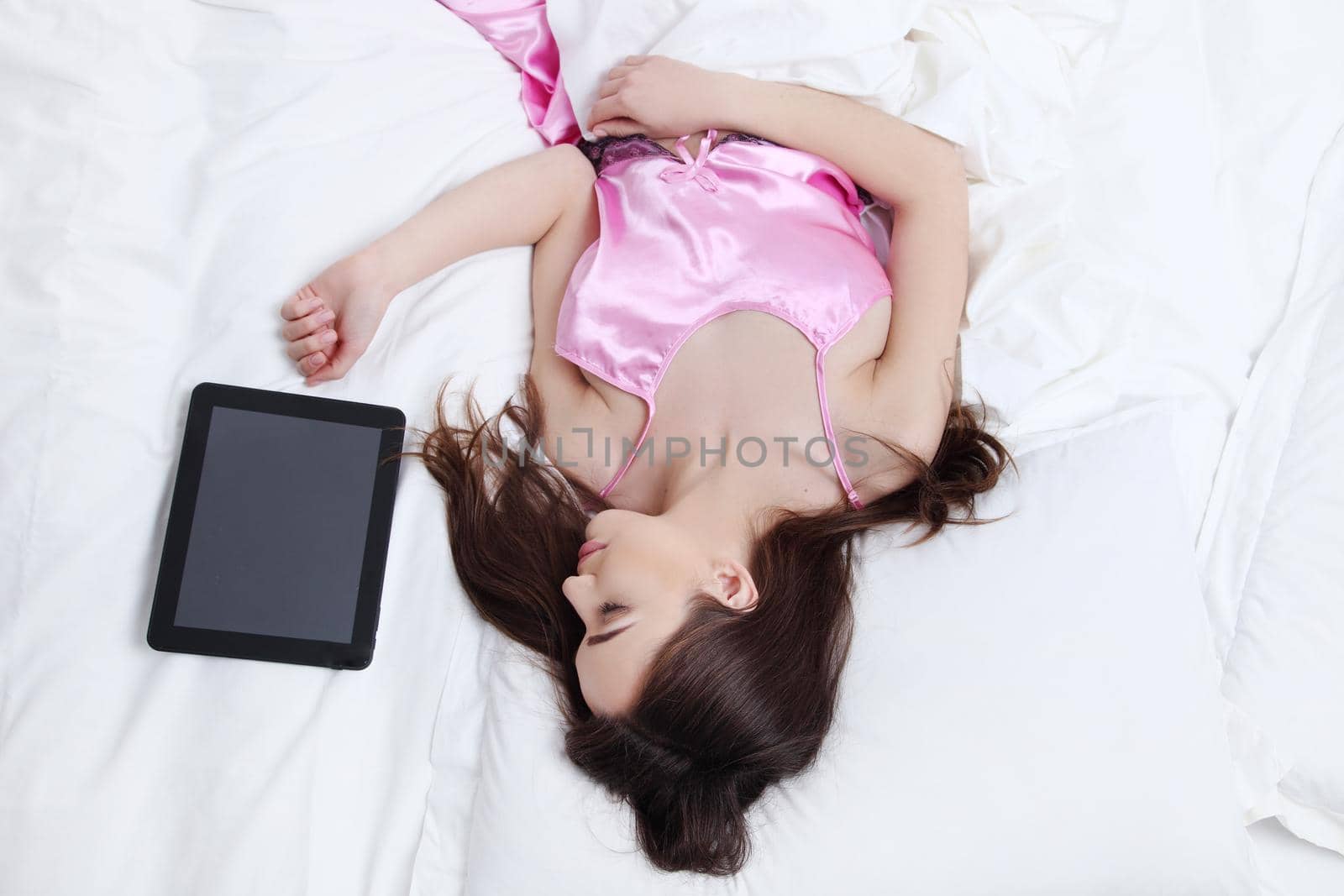woman lying in a bed of laptop on a light background