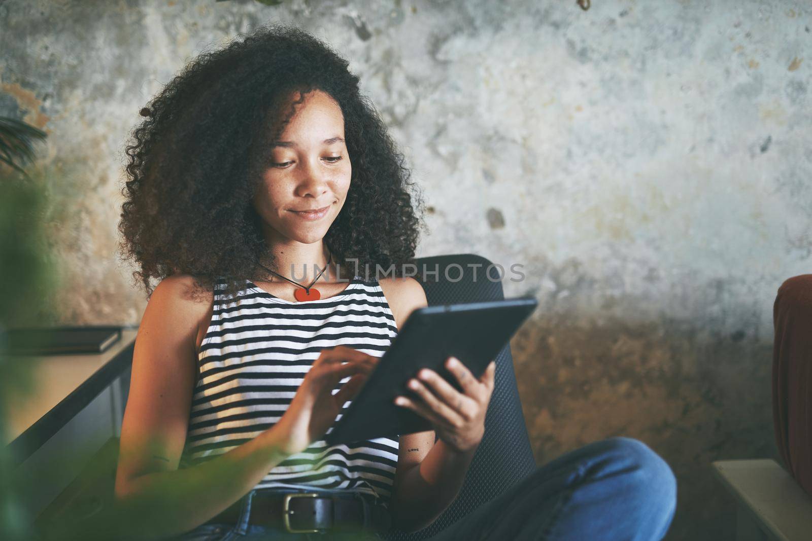 Shot of an attractive young african woman sitting alone and using her tablet while working from home stock photo