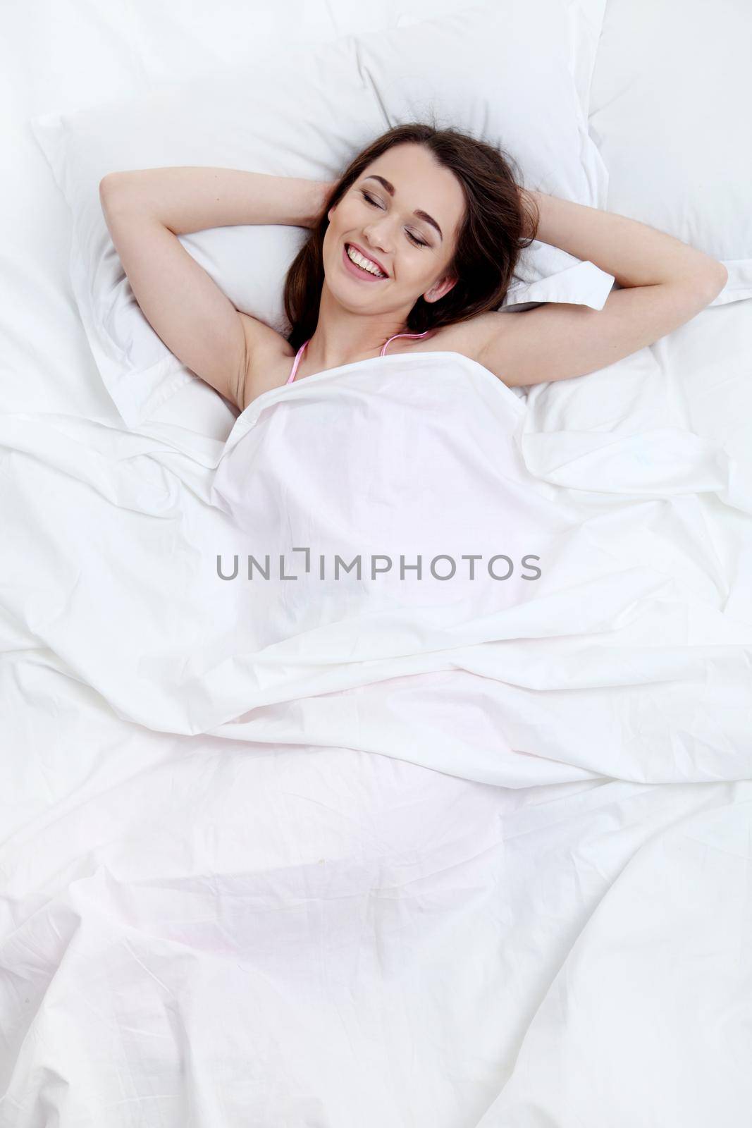 Young beautiful woman waking up in her bed fully rested. Healthy lifestyle.