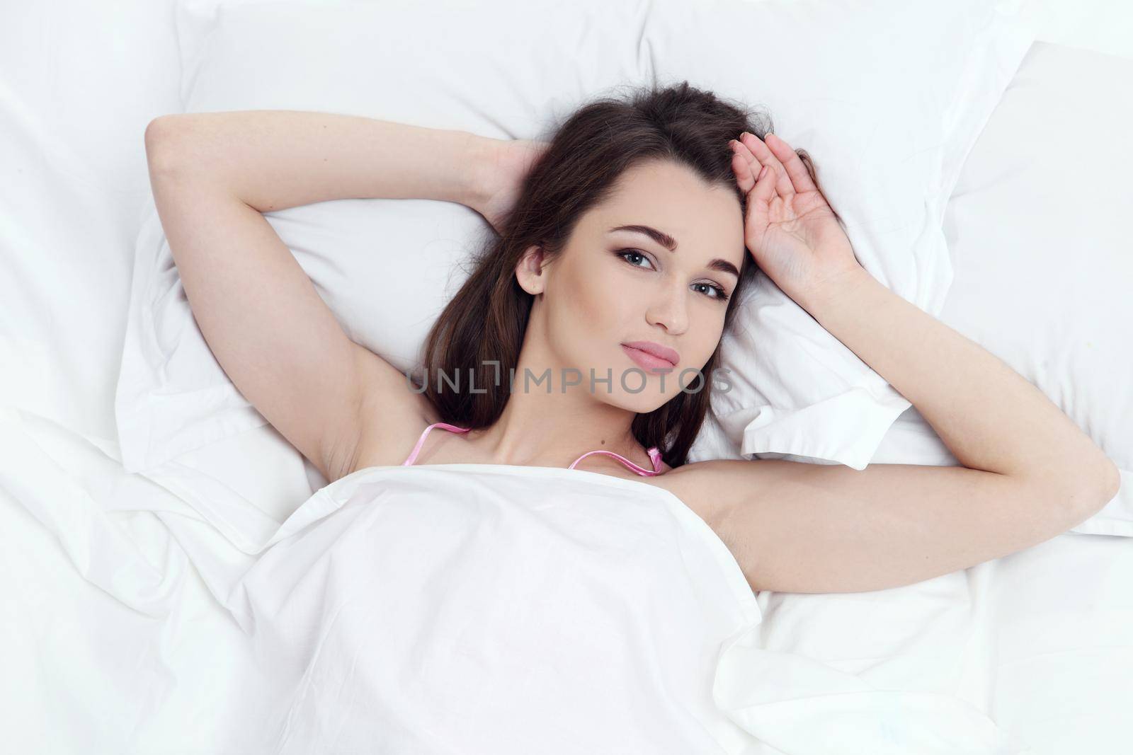 Pretty woman lying down on her bed at home.